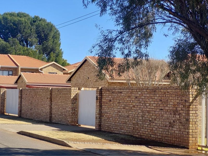 Street view of the property featuring a face-brick boundary wall, tiled roof structure, and gated entrance.