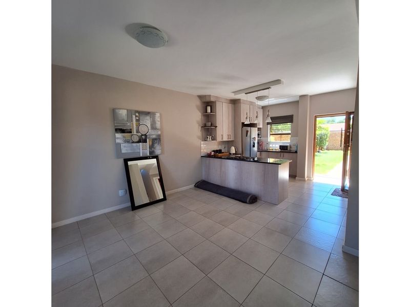 Open plan kitchen featuring light wood cabinetry, dark countertops, and tiled flooring, with direct access to the rear garden.