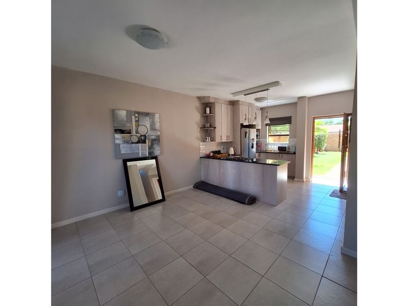 Open plan kitchen and living area featuring tiled flooring, built-in cabinetry, and direct access to the rear garden.