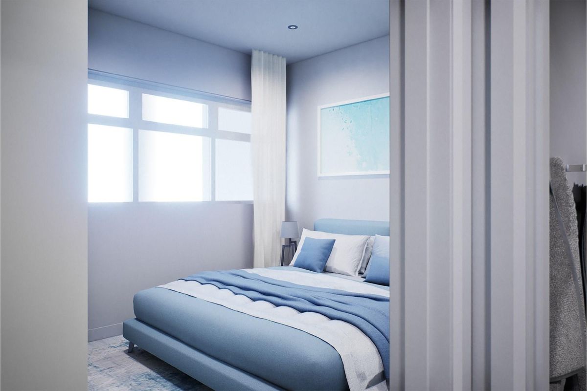 A well-lit bedroom featuring a large window, recessed ceiling lighting, and a neutral color palette, viewed from the doorway.