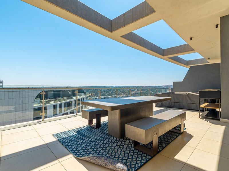Spacious modern balcony featuring a concrete pergola, glass balustrade, and expansive city views, perfect for outdoor entertaining.