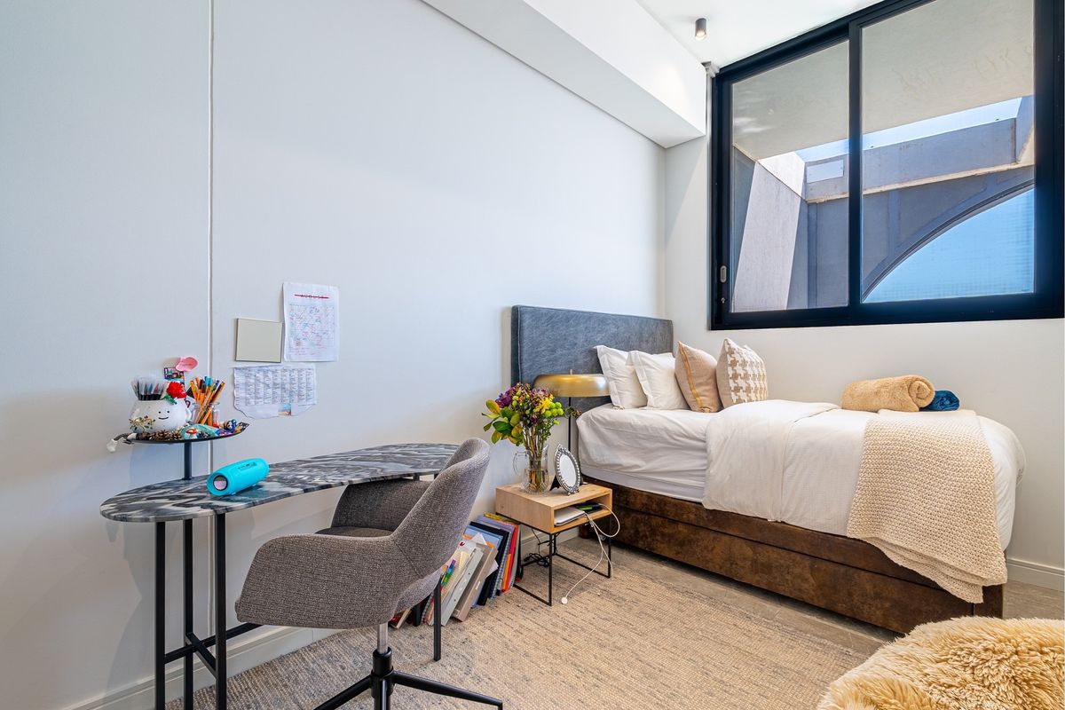 A modern, well-lit bedroom featuring a large sliding window and neutral finishes, providing a comfortable and functional living space.