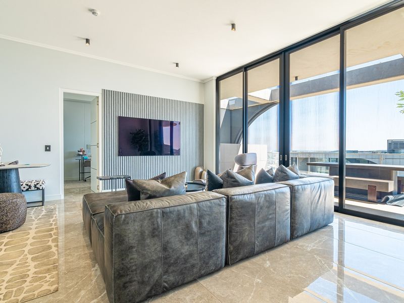 Modern living room featuring large format floor tiles, a stylish slatted timber feature wall, and expansive floor-to-ceiling glass doors leading to the balcony.