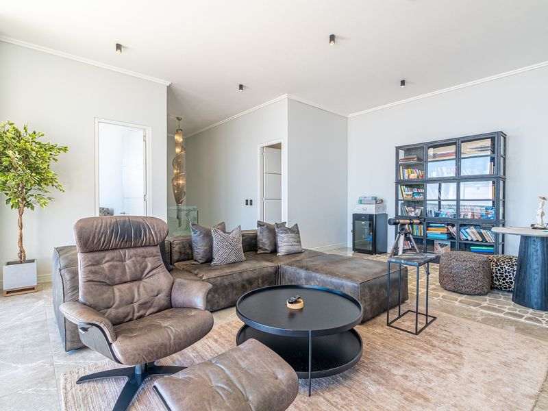 A bright and modern living room featuring stone tile flooring, recessed ceiling lighting, and elegant cove molding throughout the space.