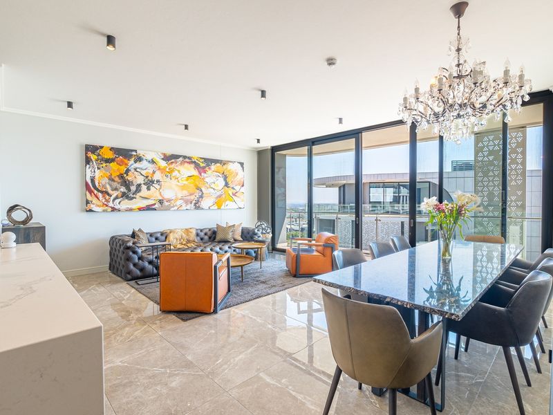 Spacious open-plan living and dining area featuring polished marble-look flooring, modern recessed lighting, and large sliding doors leading to a private balcony.