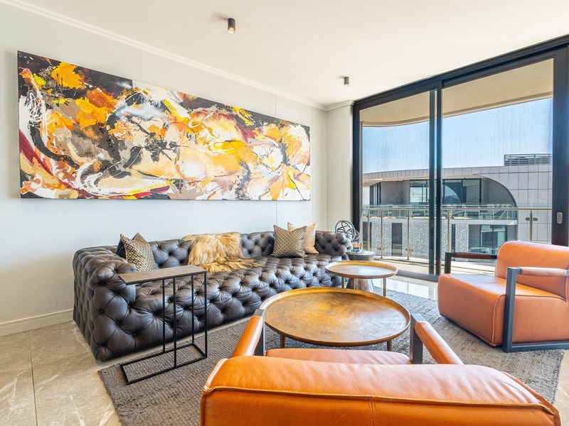 Modern living room featuring large sliding glass doors leading to a balcony, stone tile flooring, and recessed ceiling lighting.