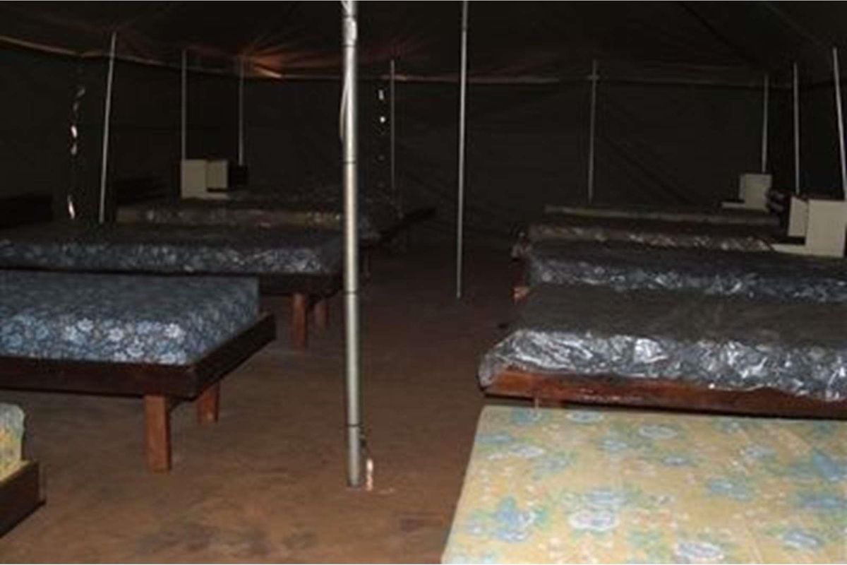A rustic tented accommodation unit featuring multiple sleeping berths within a basic canvas structure.
