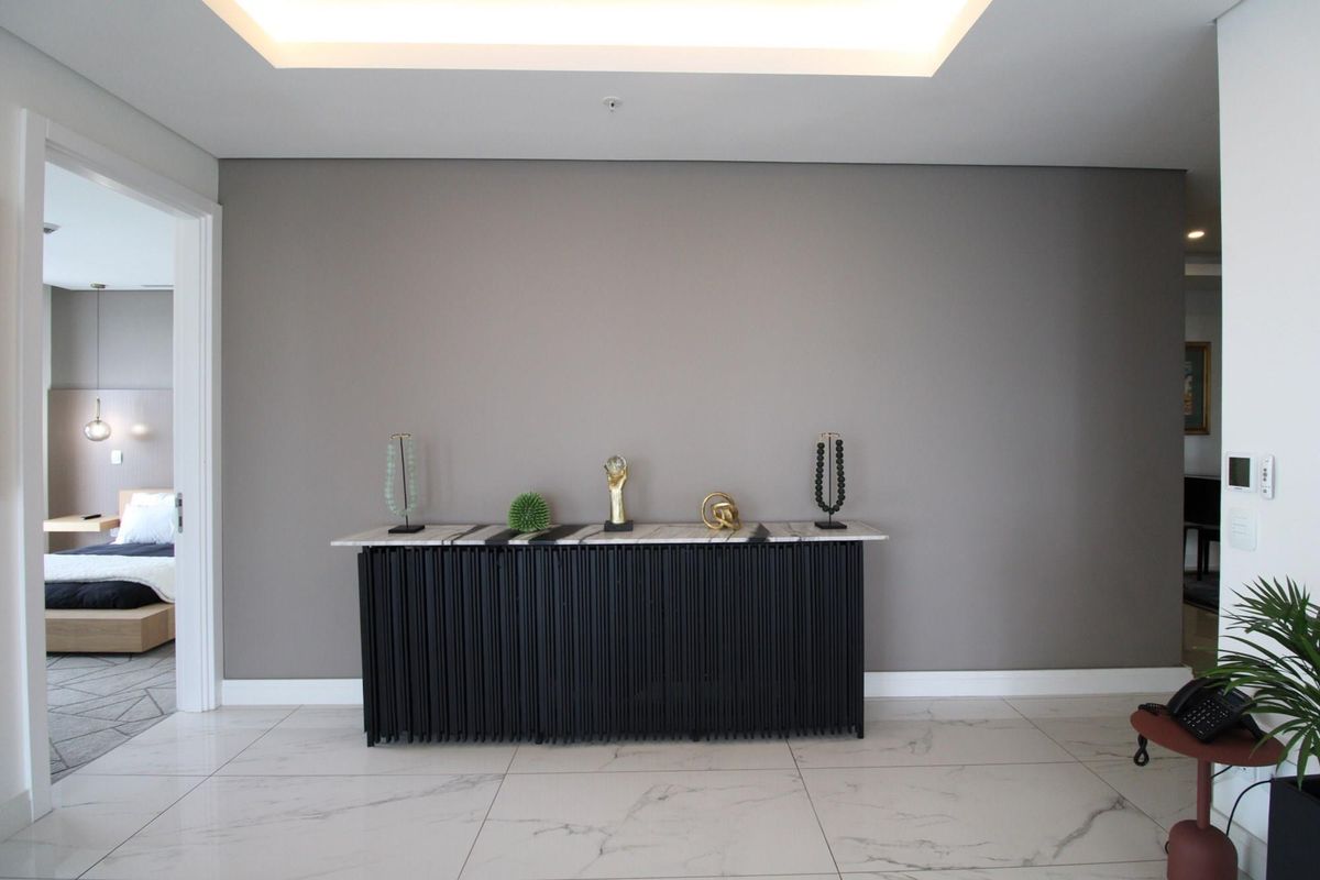A modern, well-lit interior space featuring large-format marble-look floor tiles, a recessed ceiling light feature, and a neutral grey accent wall.