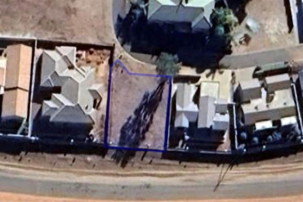 An aerial view of a vacant residential plot situated between existing properties, highlighting the available land area and its position within the neighborhood.
