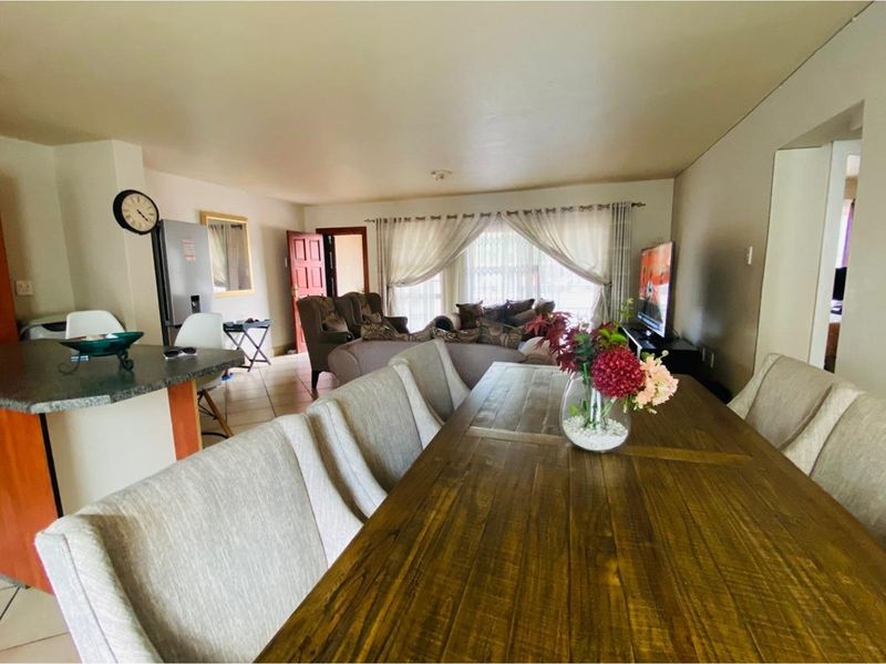 Open-plan living and dining area featuring tiled flooring, a breakfast bar, and large windows allowing for natural light.