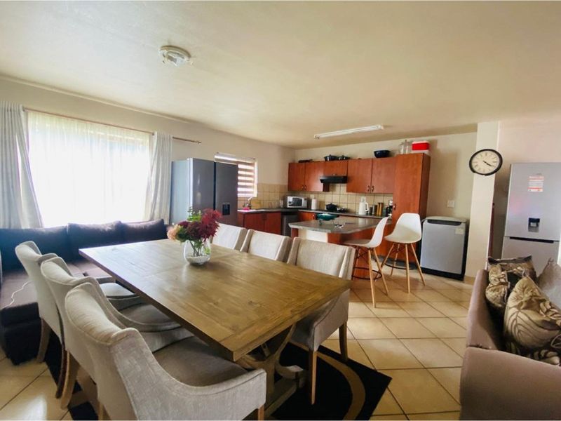 Open-plan living and dining area featuring a functional kitchen with wooden cabinetry, tiled flooring, and a breakfast counter.
