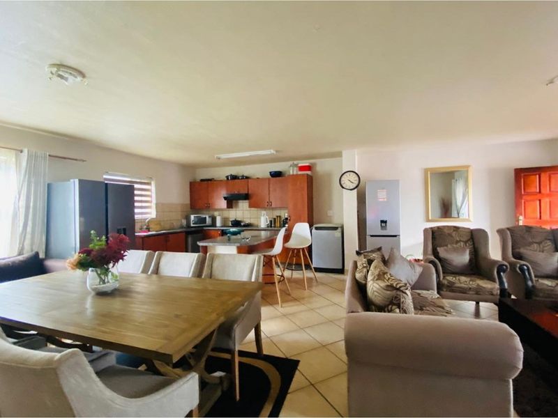 Open plan living and dining area featuring a functional kitchen with wooden cabinetry and tiled flooring throughout.