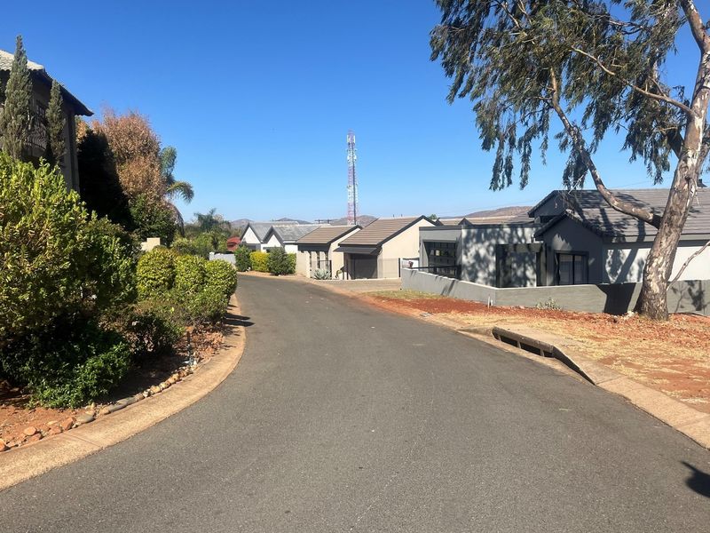 A view of a residential street within a housing estate, featuring paved roads, established landscaping, and surrounding residential properties.