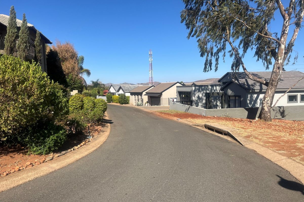 A view of a residential street within a housing estate, featuring paved roads, established landscaping, and surrounding residential properties.