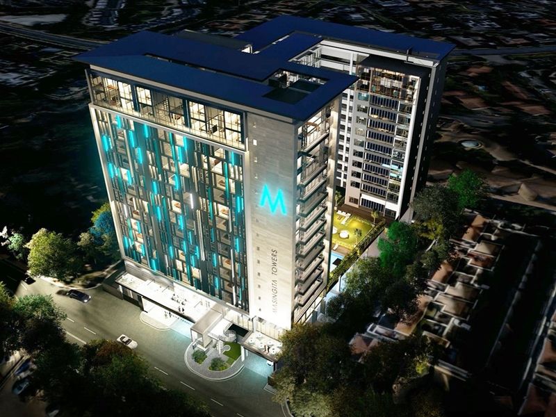 An aerial night view of the Masingita Towers high-rise building, showcasing its modern architectural design, facade lighting, and surrounding landscaped grounds.