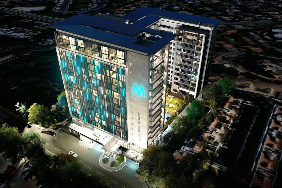 An aerial night view of the Masingita Towers high-rise building, showcasing its modern architectural design, facade lighting, and surrounding landscaped grounds.