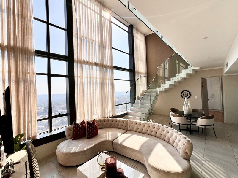 Spacious double-volume living area featuring floor-to-ceiling windows with panoramic views and a modern floating glass staircase.
