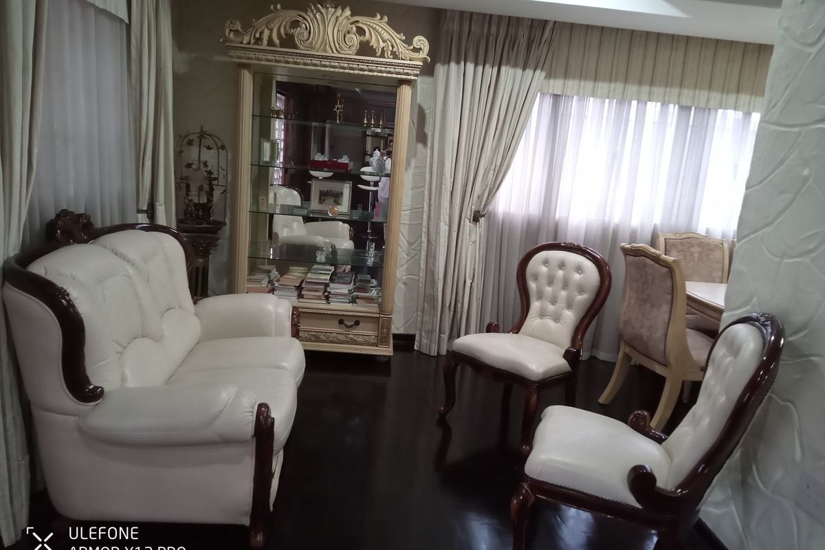 A formal living area featuring dark hardwood flooring and classic window treatments, providing a traditional and structured space for relaxation.