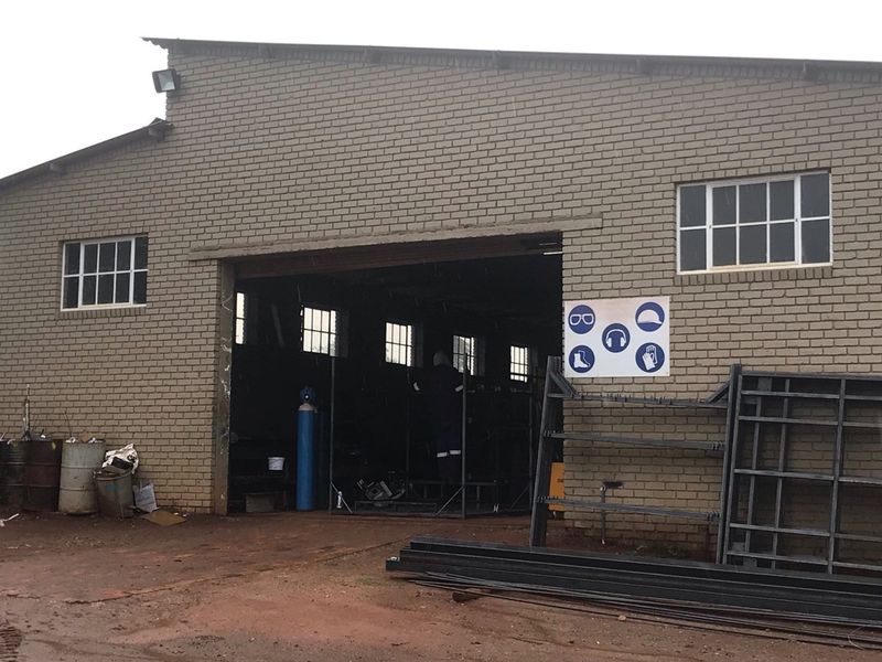 A functional farm workshop or utility building featuring brick construction, large access opening, and exterior security lighting.