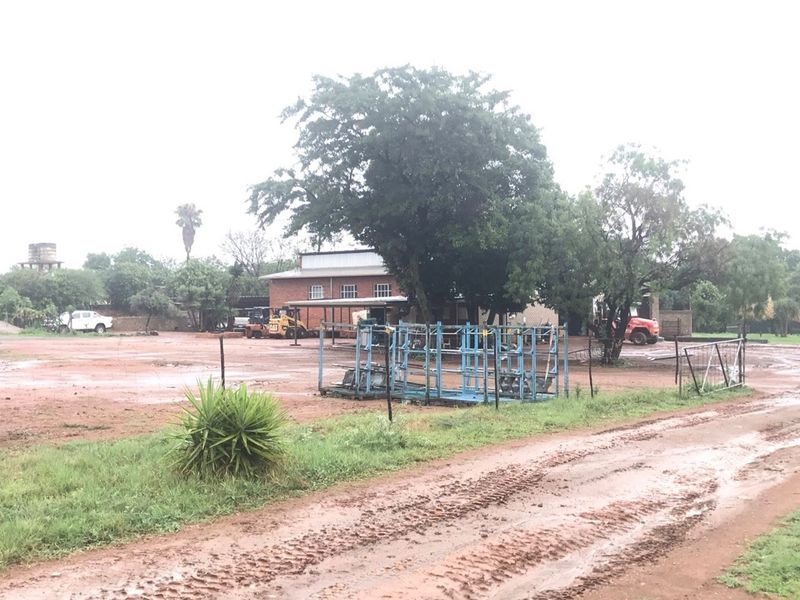 A wide view of the farm property featuring a brick building, open yard space, and unpaved access tracks.