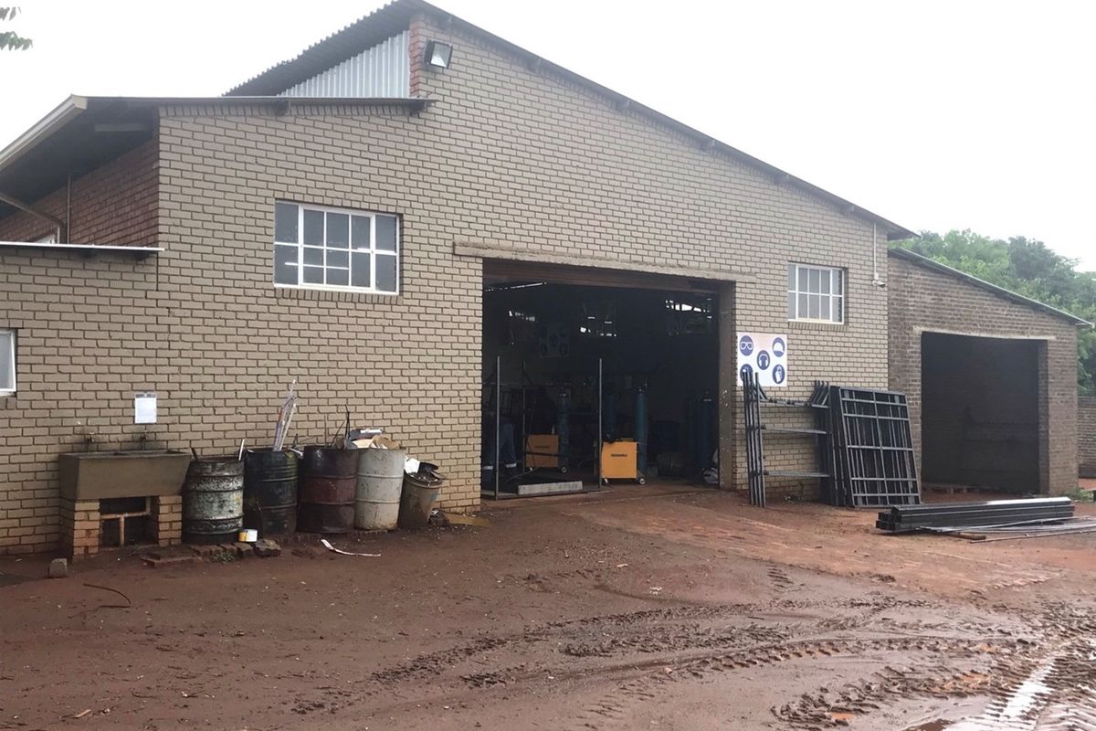 A functional farm utility building featuring brick construction, large open access bay, and an external utility sink area.