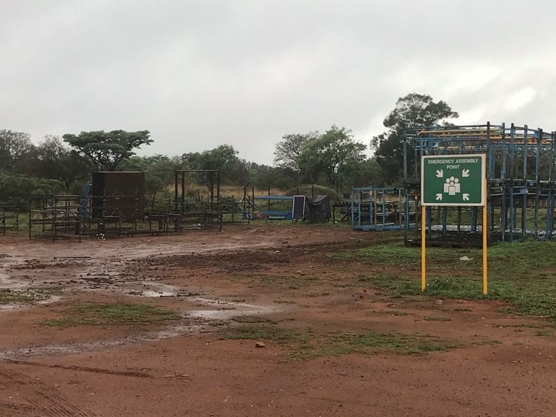 An outdoor utility area on the farm property featuring an emergency assembly point sign and various metal structural components.