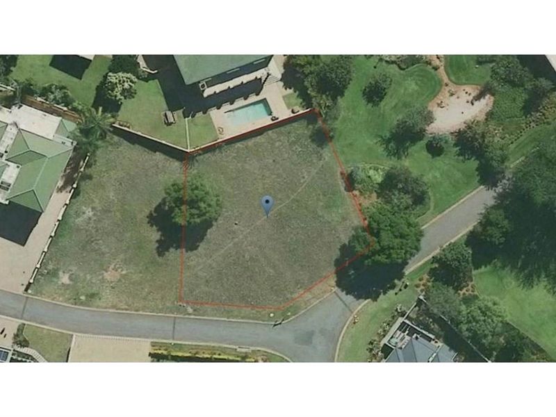 An aerial view of a vacant residential plot featuring established trees and clear boundary lines within a developed neighborhood setting.