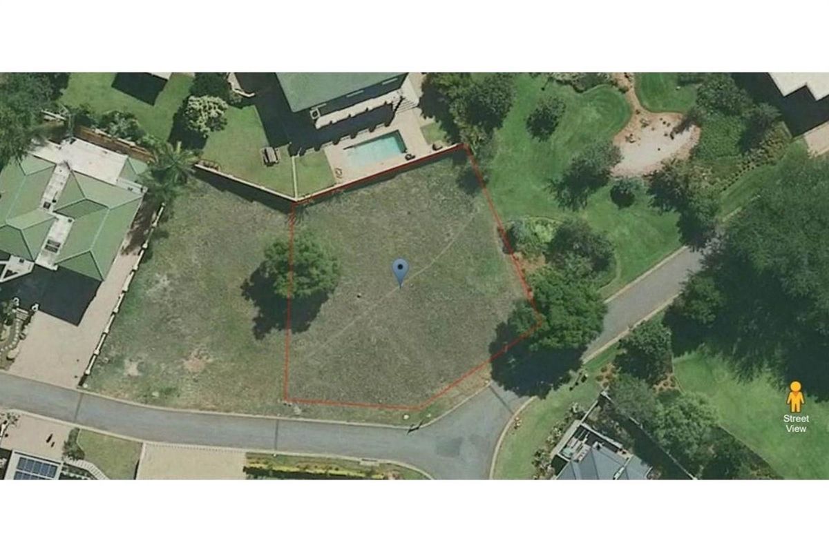 An aerial view of a vacant residential plot featuring established trees and clear boundary lines within a developed neighborhood setting.