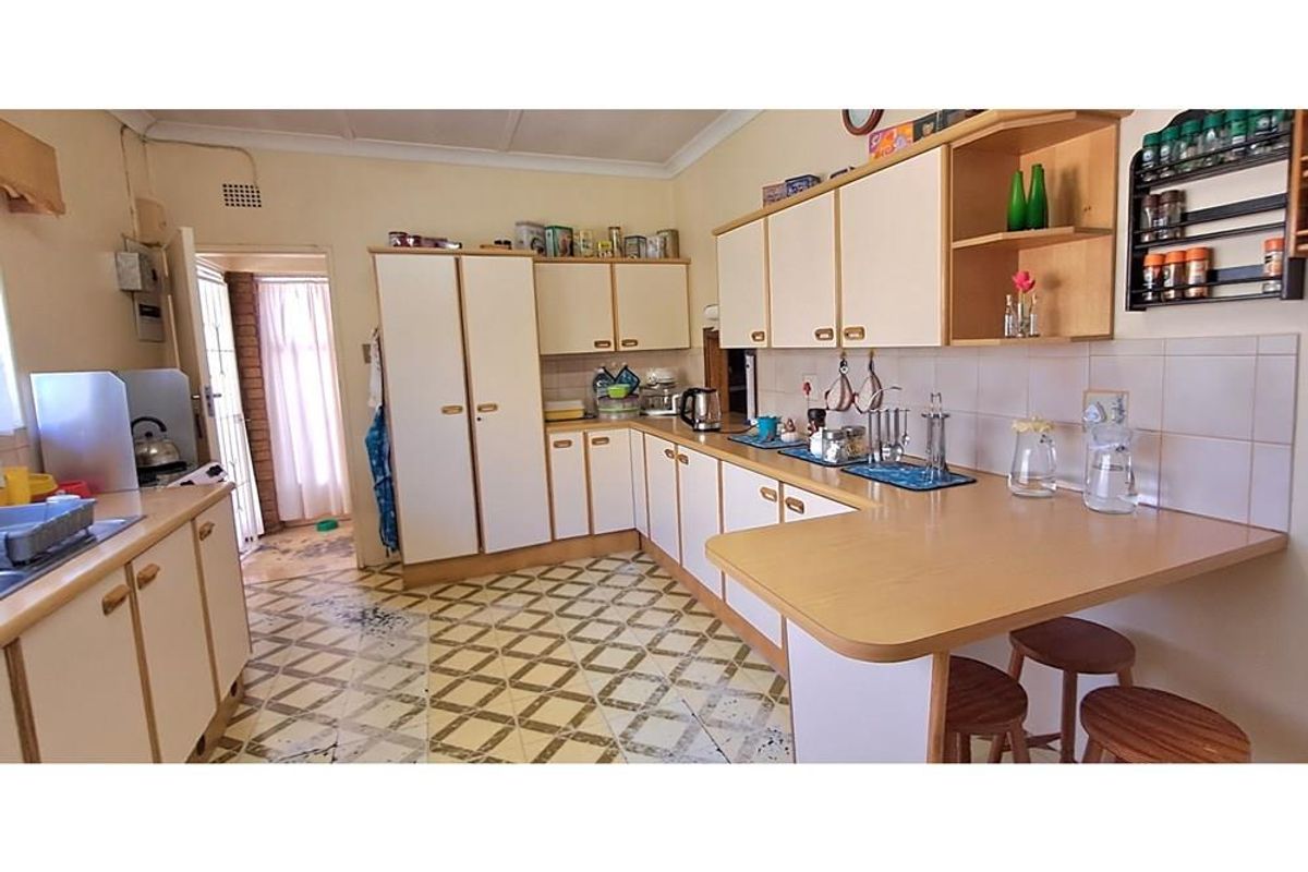 A functional kitchen featuring laminate cabinetry, a breakfast bar, and tiled flooring, offering a practical layout with potential for modern updates.