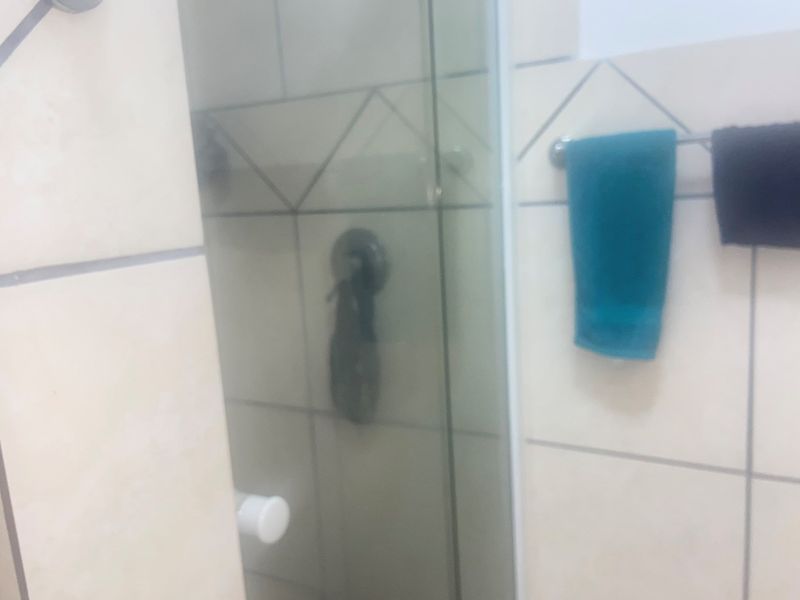 A close-up view of a bathroom shower area featuring a glass enclosure and tiled walls.