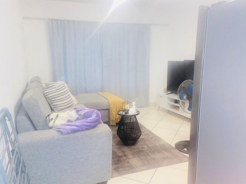 A living room area featuring tiled flooring and a curtain rail, presented in a bright, neutral space.