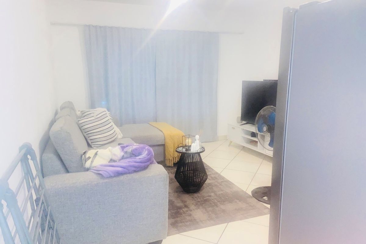 A living room area featuring tiled flooring and a curtain rail, presented in a bright, neutral space.