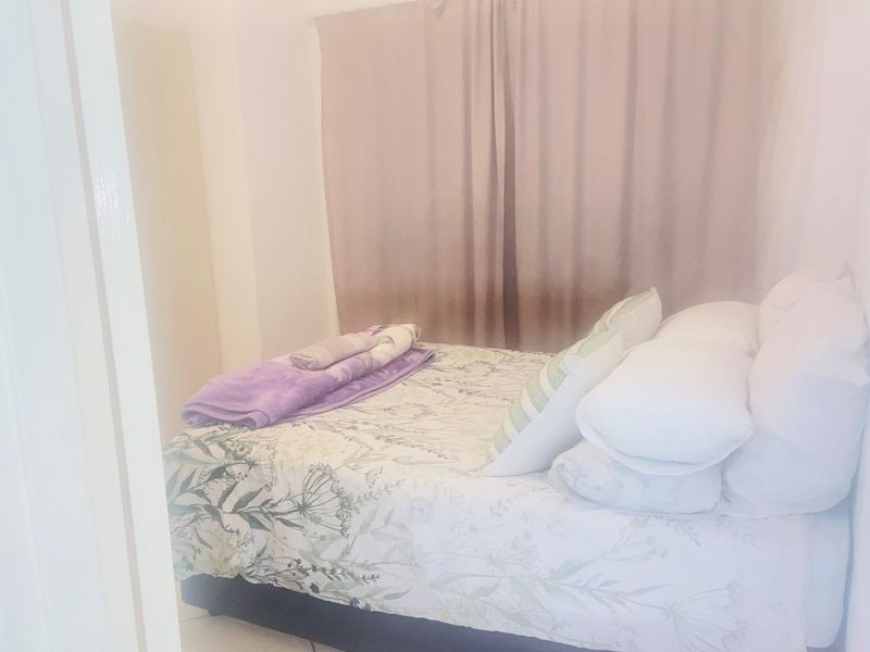 A compact bedroom featuring neutral wall finishes and window treatments, providing a functional sleeping space within the apartment.