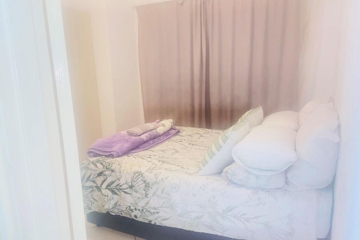A compact bedroom featuring neutral wall finishes and window treatments, providing a functional sleeping space within the apartment.