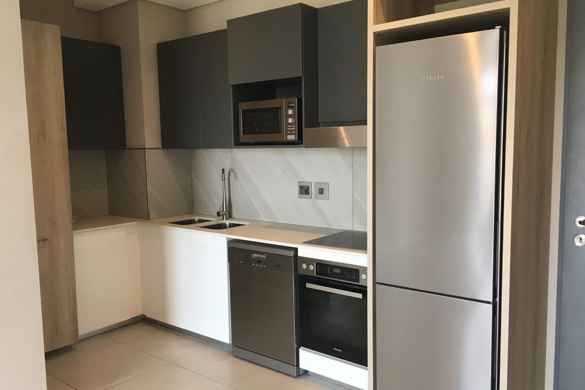Modern kitchen featuring sleek dark grey and white cabinetry, integrated stainless steel appliances, stone countertops, and a contemporary tiled backsplash.