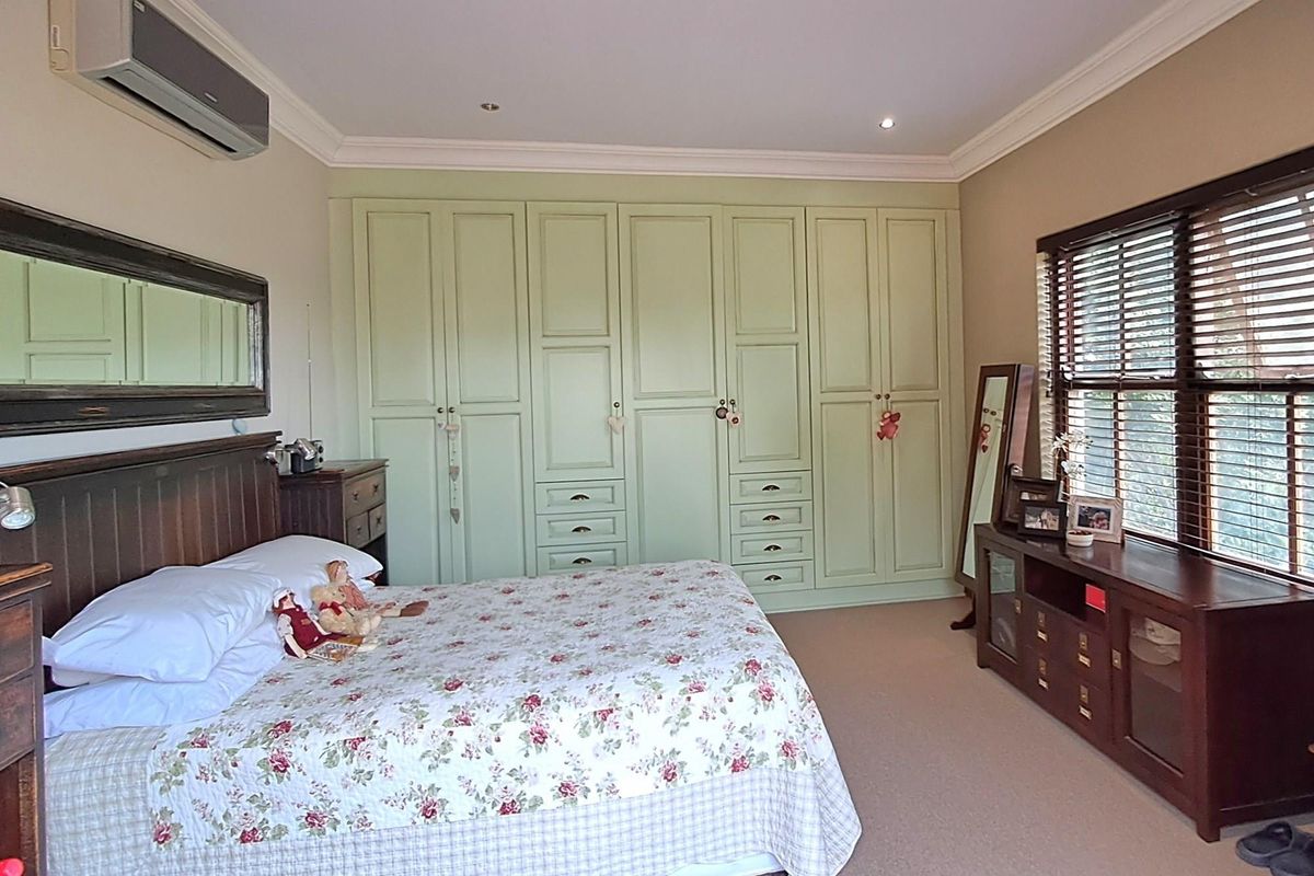 A well-maintained bedroom featuring extensive built-in cabinetry, recessed ceiling lighting, and a wall-mounted air conditioning unit.