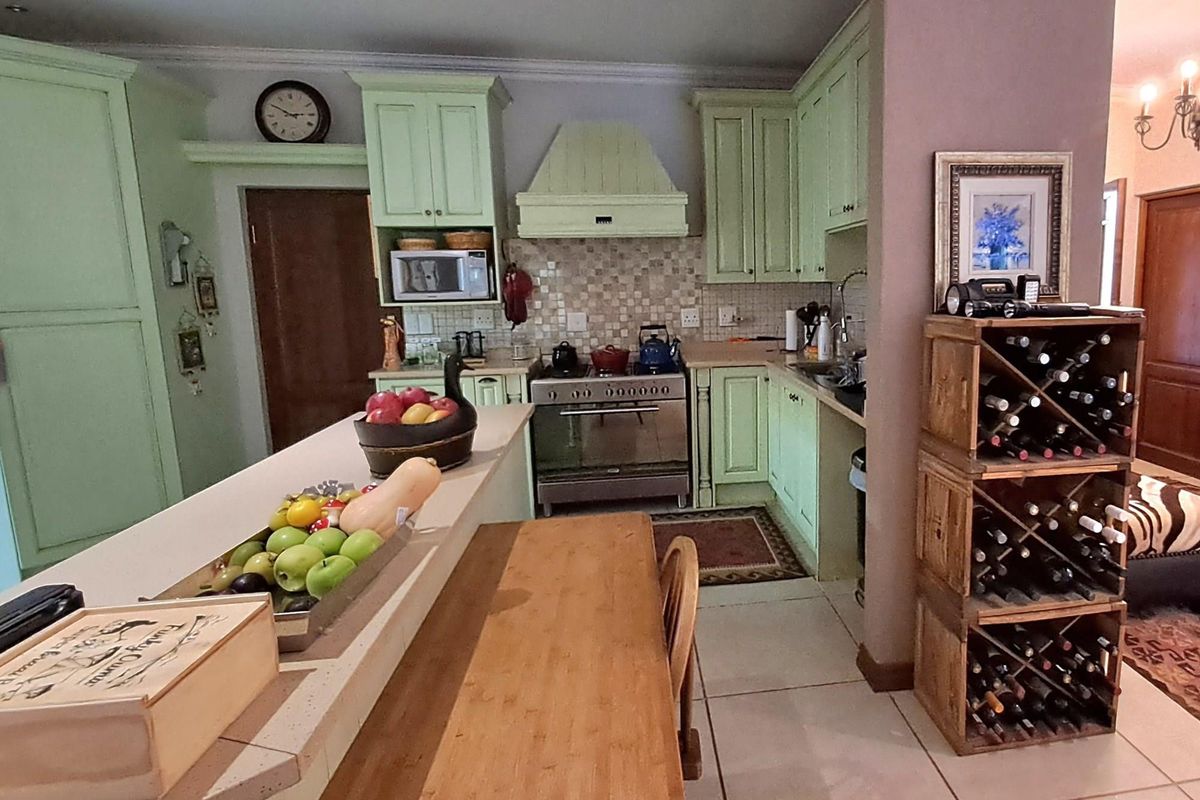 A functional kitchen featuring light green cabinetry, a tiled backsplash, a built-in extractor hood, and a breakfast bar counter.