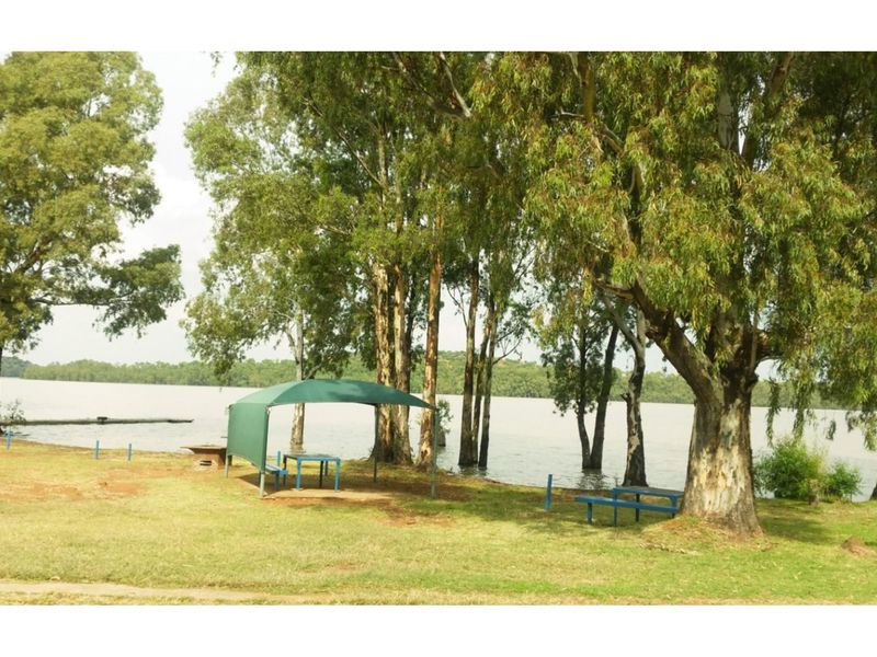 A scenic waterfront garden area featuring mature trees and direct access to the lake, providing a peaceful outdoor setting.