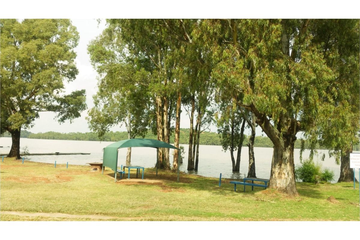 A scenic waterfront garden area featuring mature trees and direct access to the lake, providing a peaceful outdoor setting.