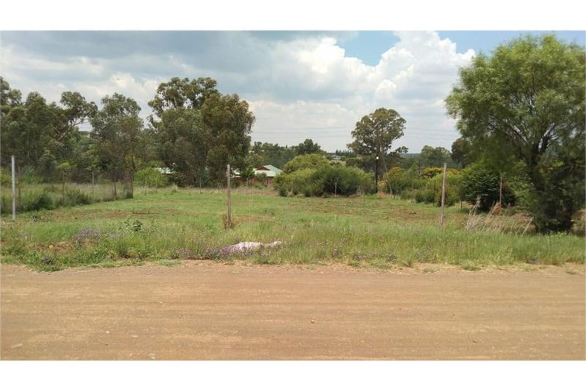 A vacant residential plot featuring natural vegetation, wire fencing, and direct access from an unpaved road.
