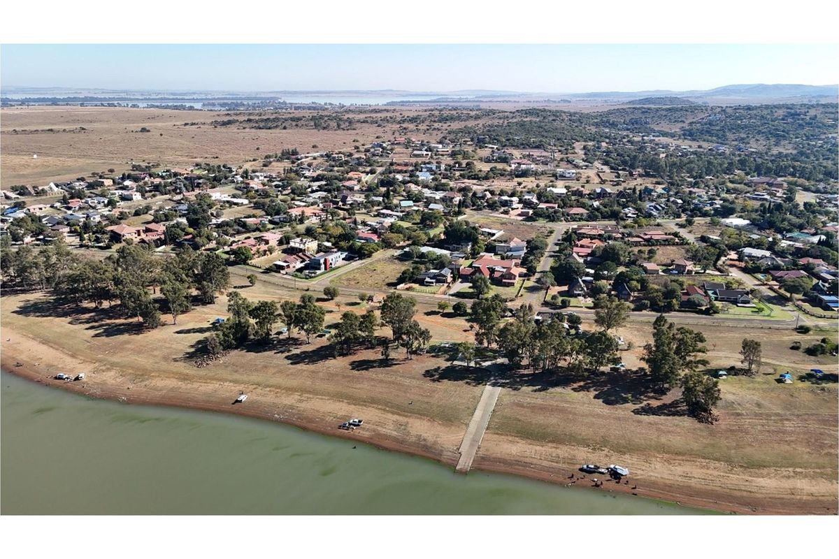 Aerial view of a residential area situated along a waterfront, featuring a concrete boat ramp and surrounding natural landscape.