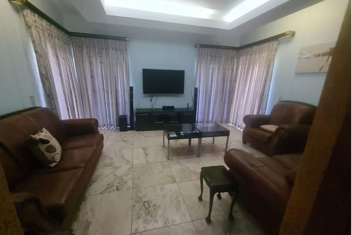 Spacious living room featuring large format marble-style floor tiles, recessed tray ceiling with integrated lighting, and dual sliding glass doors with curtain tracks.