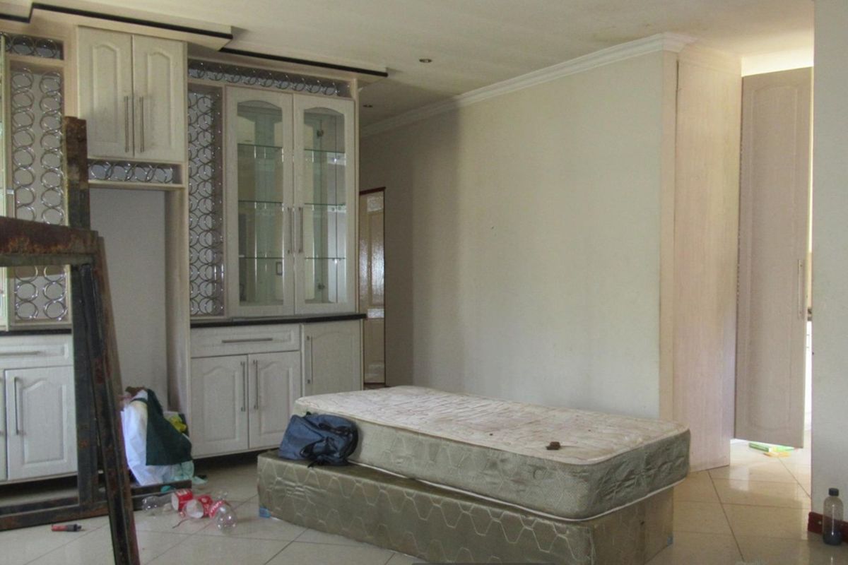 A living area featuring built-in cabinetry with glass display panels and tiled flooring, offering a functional space with potential for modernization.