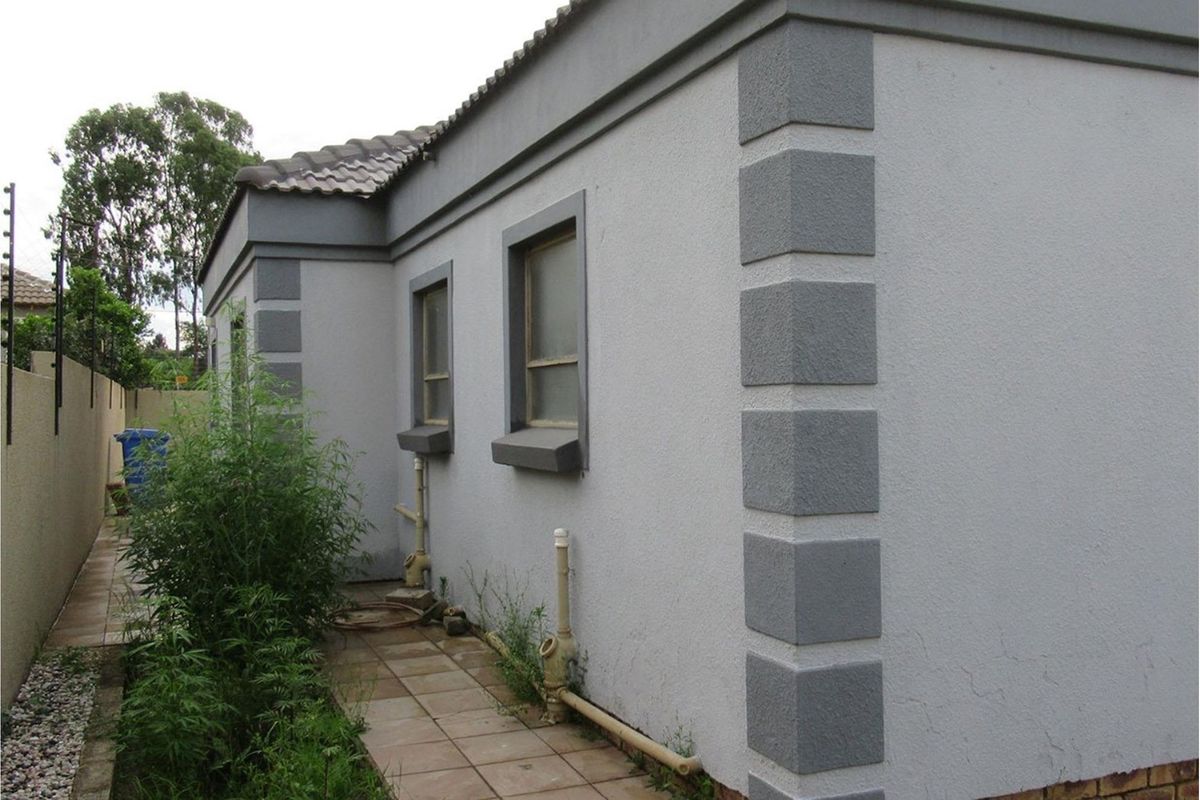 Side exterior view of the house featuring painted masonry walls with decorative corner quoins and tiled pathway.