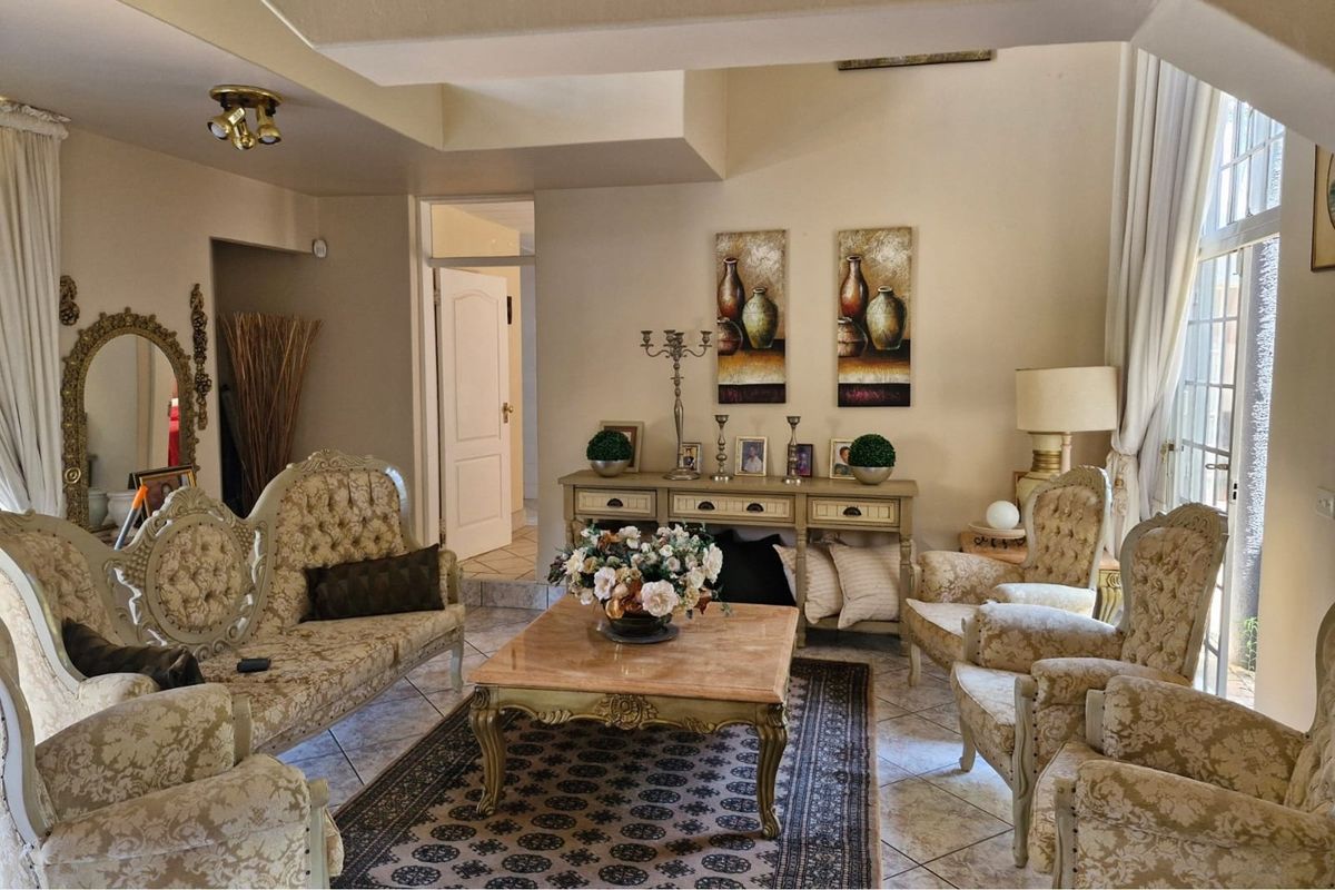 A spacious living room featuring tiled flooring, high ceilings, and large windows that provide ample natural light.