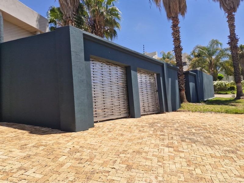 A double garage with modern metallic roller doors and a paved driveway, set within a landscaped residential property.