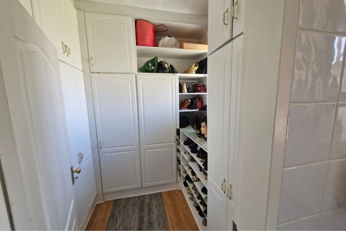 A walk-in closet or dressing area featuring extensive built-in white cabinetry with ample shelving and storage space.