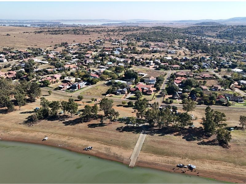 Aerial view of a residential area featuring a concrete boat ramp providing direct access to the waterfront and surrounding natural landscape.