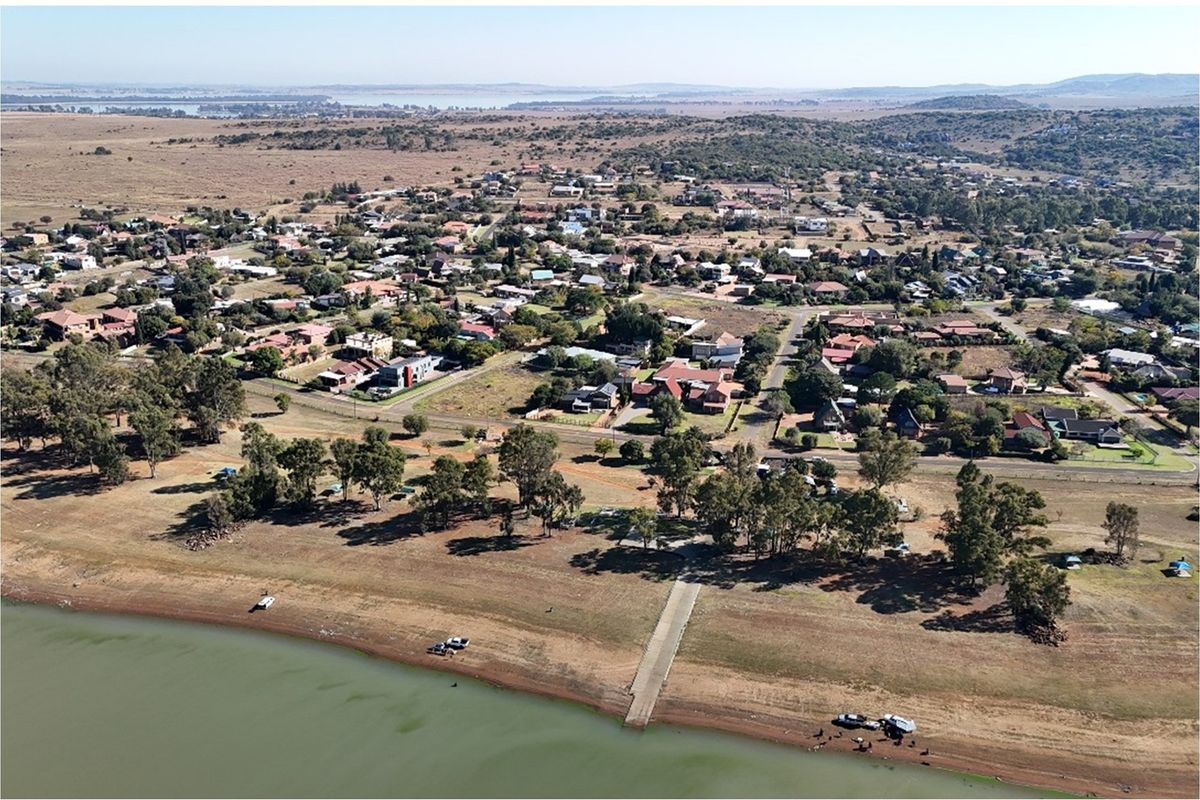 Aerial view of a residential area featuring a concrete boat ramp providing direct access to the waterfront and surrounding natural landscape.