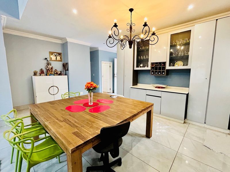 A bright dining area featuring polished floor tiles, built-in cabinetry with glass display sections, and a decorative chandelier.